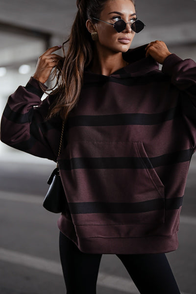Woman wearing a maroon hoodie with black stripes in an urban setting