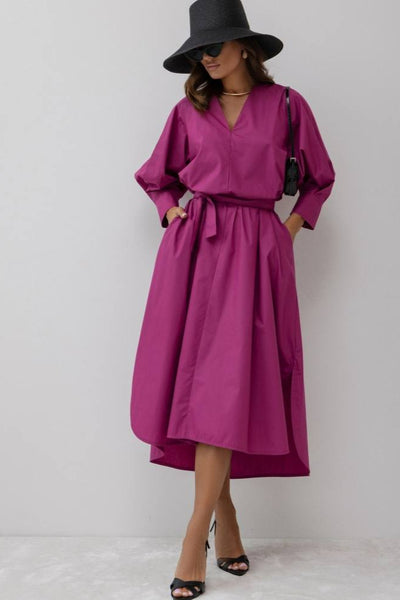 Woman wearing a magenta dress and black hat on a white background