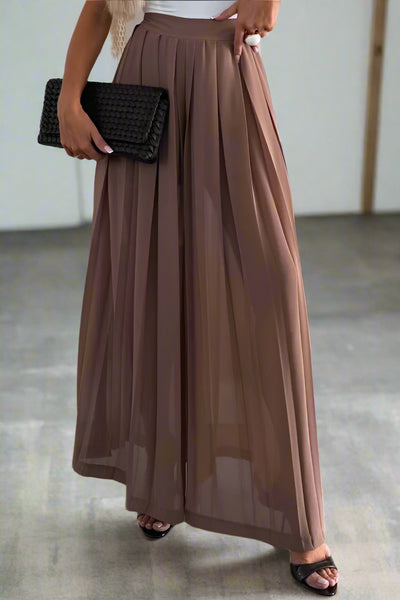 Woman in a white top and brown skirt standing in a clothing store.